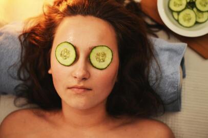 Woman with sliced cucumbers on eyes
