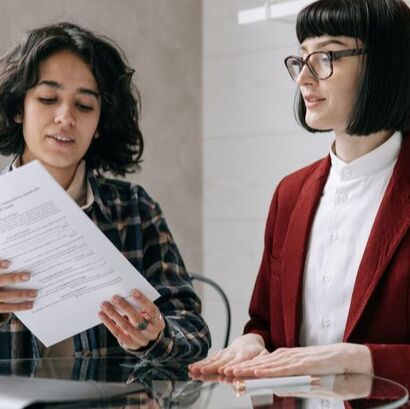 Two women, one holding paperwork.